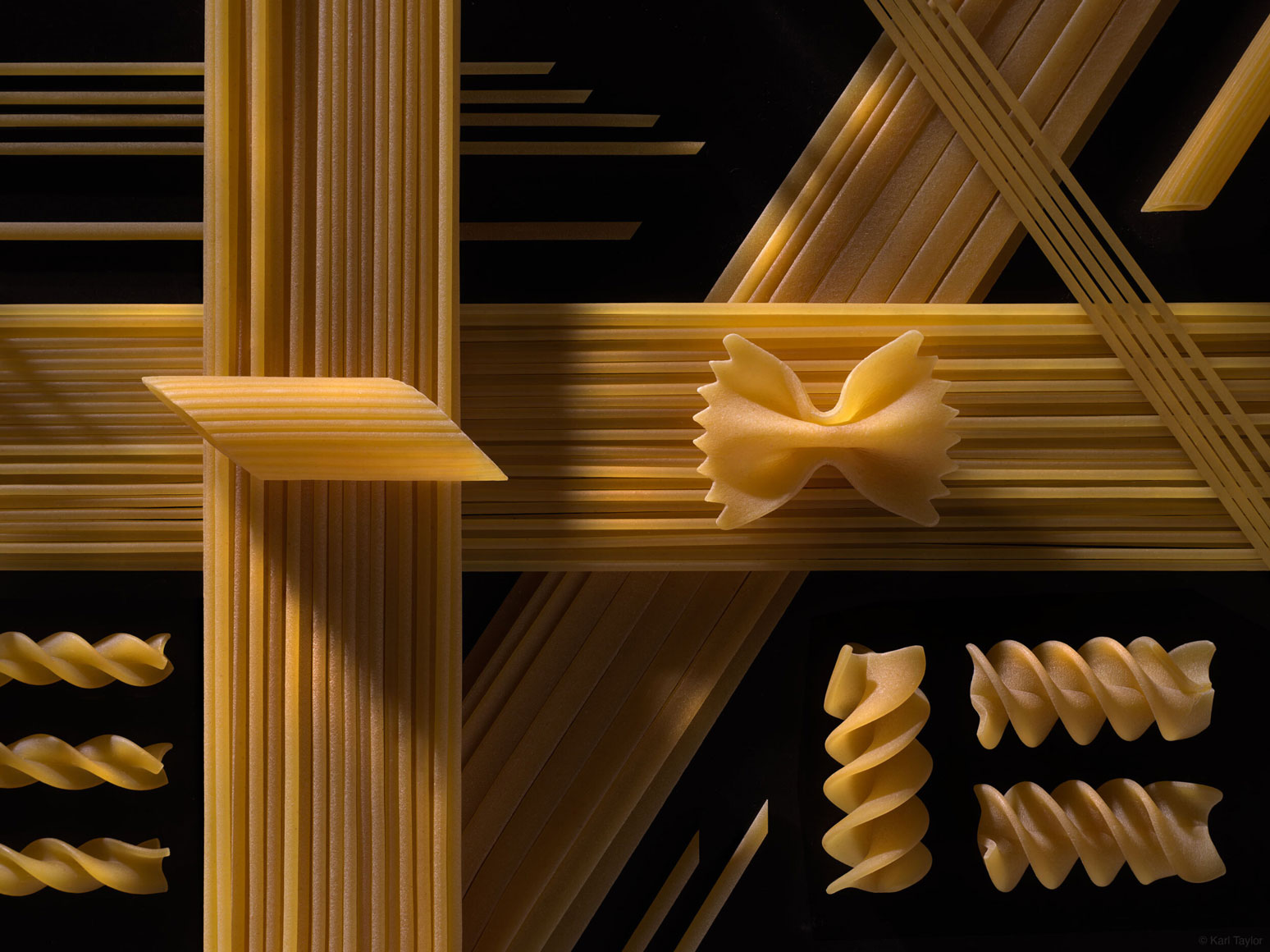 Still life image of pasta arranged on a dark background with moody shadow lighting