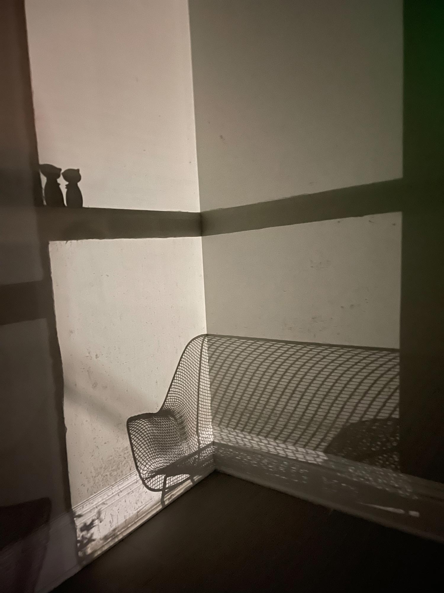 Shadow of chair and ornaments on corner of room wall